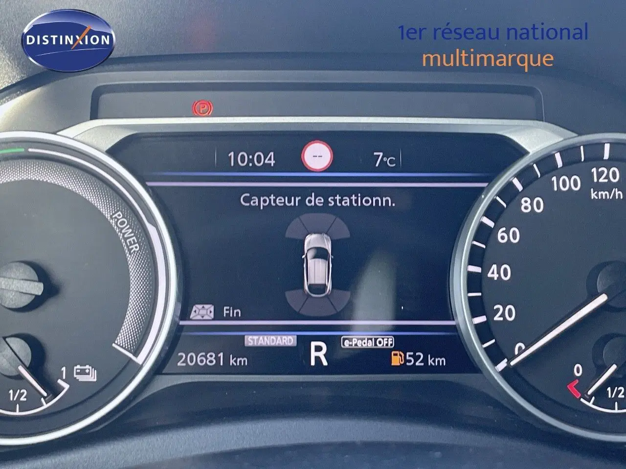 Tableau de bord du Nissan Juke gris squale métal 2024, affichant le capteur de stationnement et la vitesse à l'arrêt.