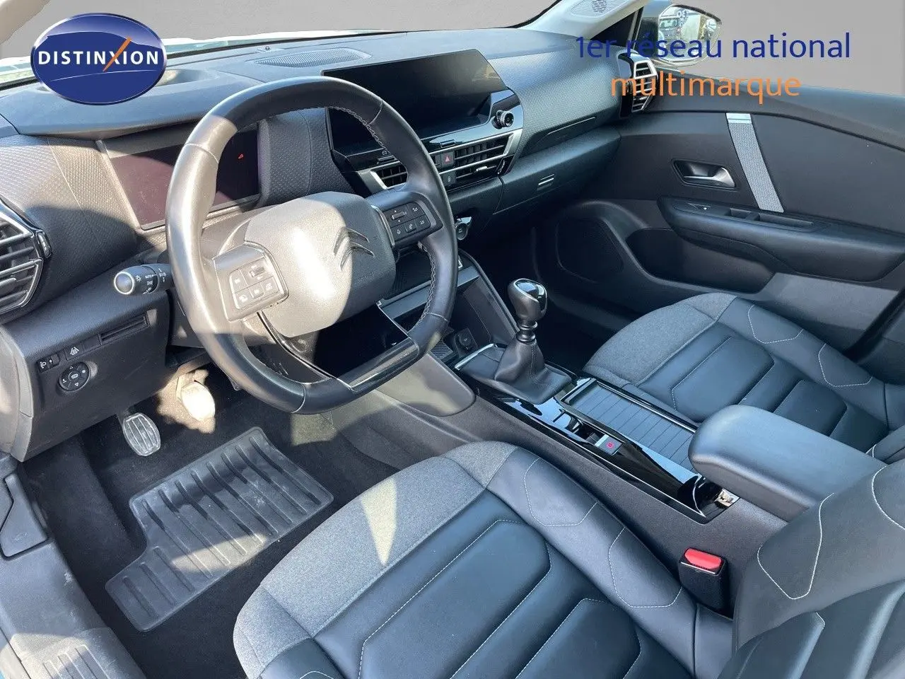 Vue intérieure côté conducteur de la Citroën C4 1.2 PureTech 130ch avec volant cuir et sellerie bi-matière gris et noir.