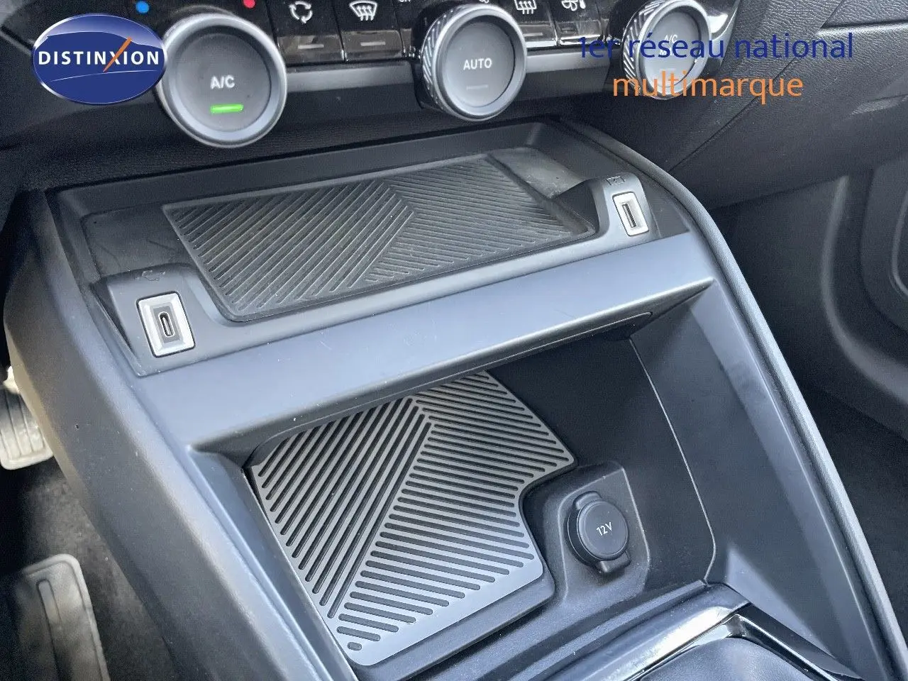 Gros plan sur la console centrale avant de la Citroën C4 bleu Iceland Metal, montrant la prise 12V et les commandes de climatisation.