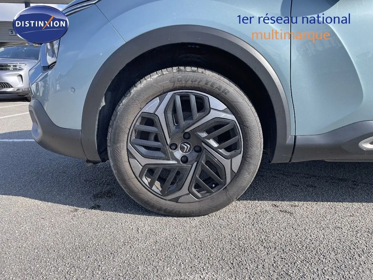 Gros plan sur la roue avant gauche d'une Citroën C4 bleu Iceland Metal avec jante noire au design géométrique.