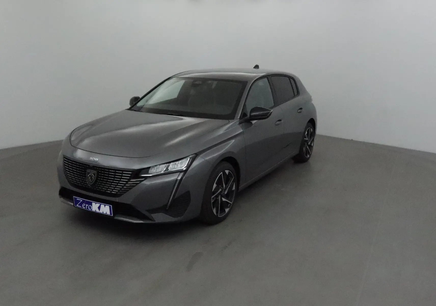Peugeot 308 gris selenium vue 3/4 avant droit dans un studio, avec calandre noire et jantes alliage.