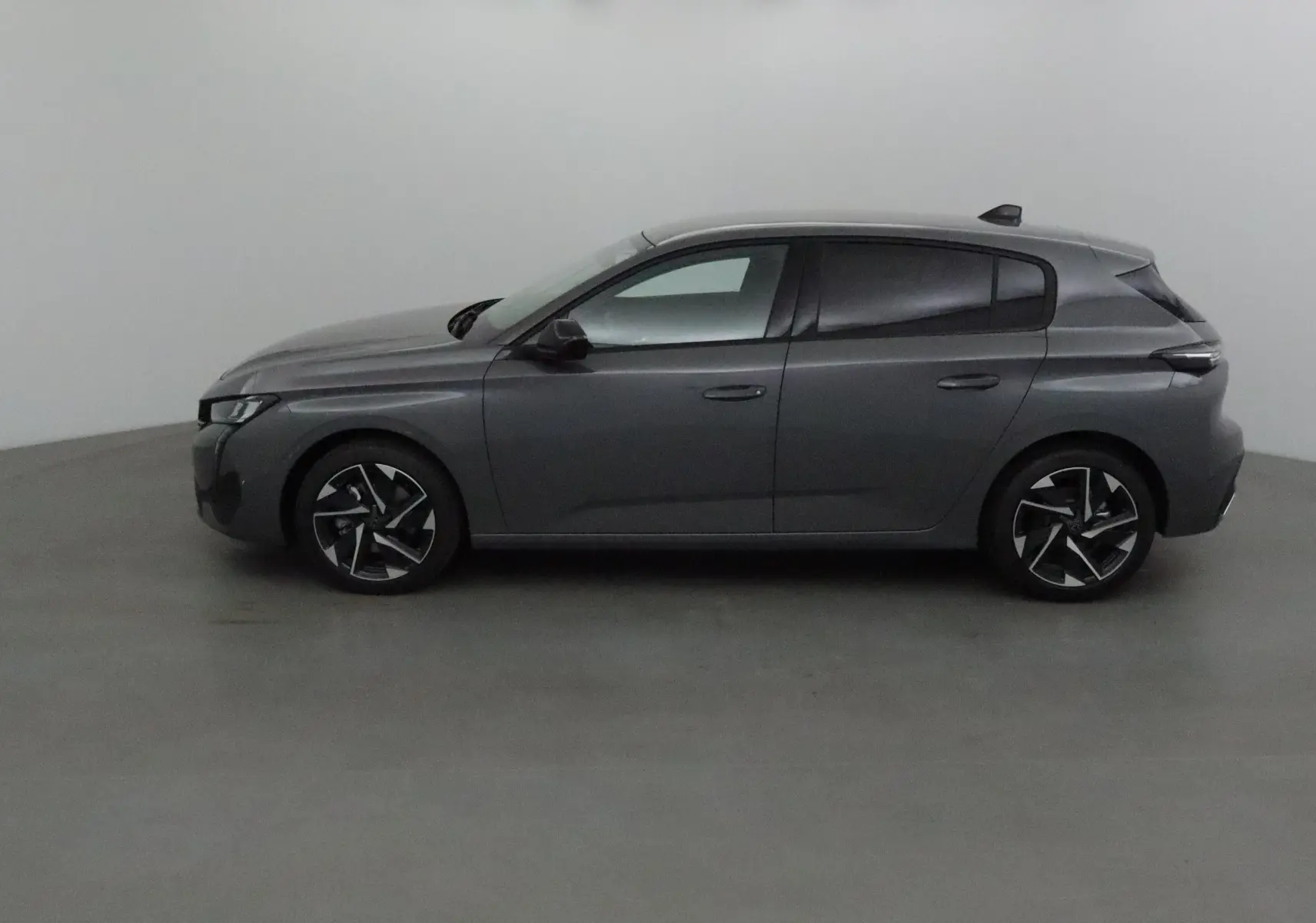 Profil côté gauche d'une Peugeot 308 gris sélénium avec jantes alliage et vitres teintées dans un studio neutre.