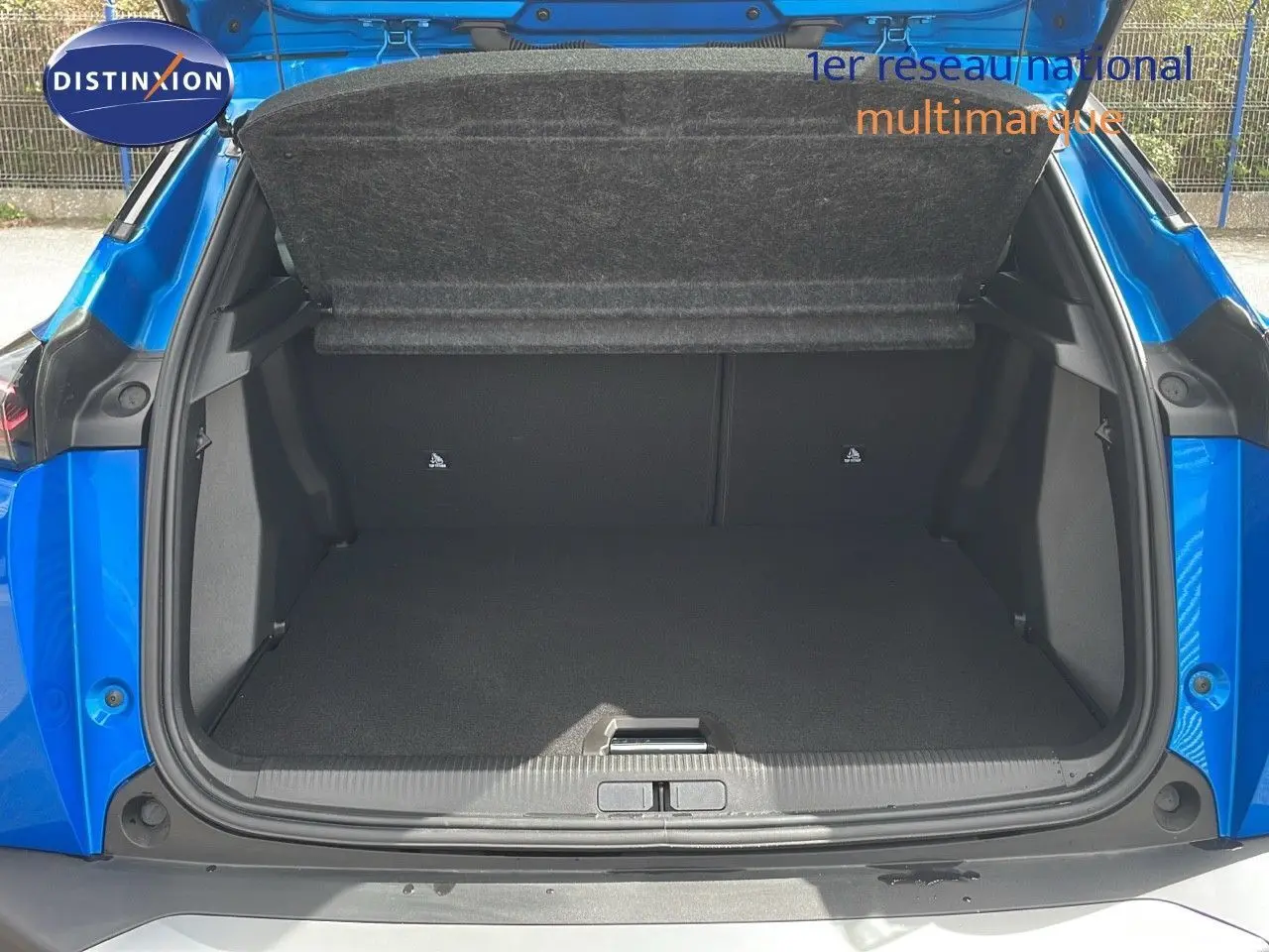 Coffre ouvert en vue arrière d'un Peugeot 2008 1.2 PureTech bleu Vertigo Métal, montrant un espace de chargement vide.