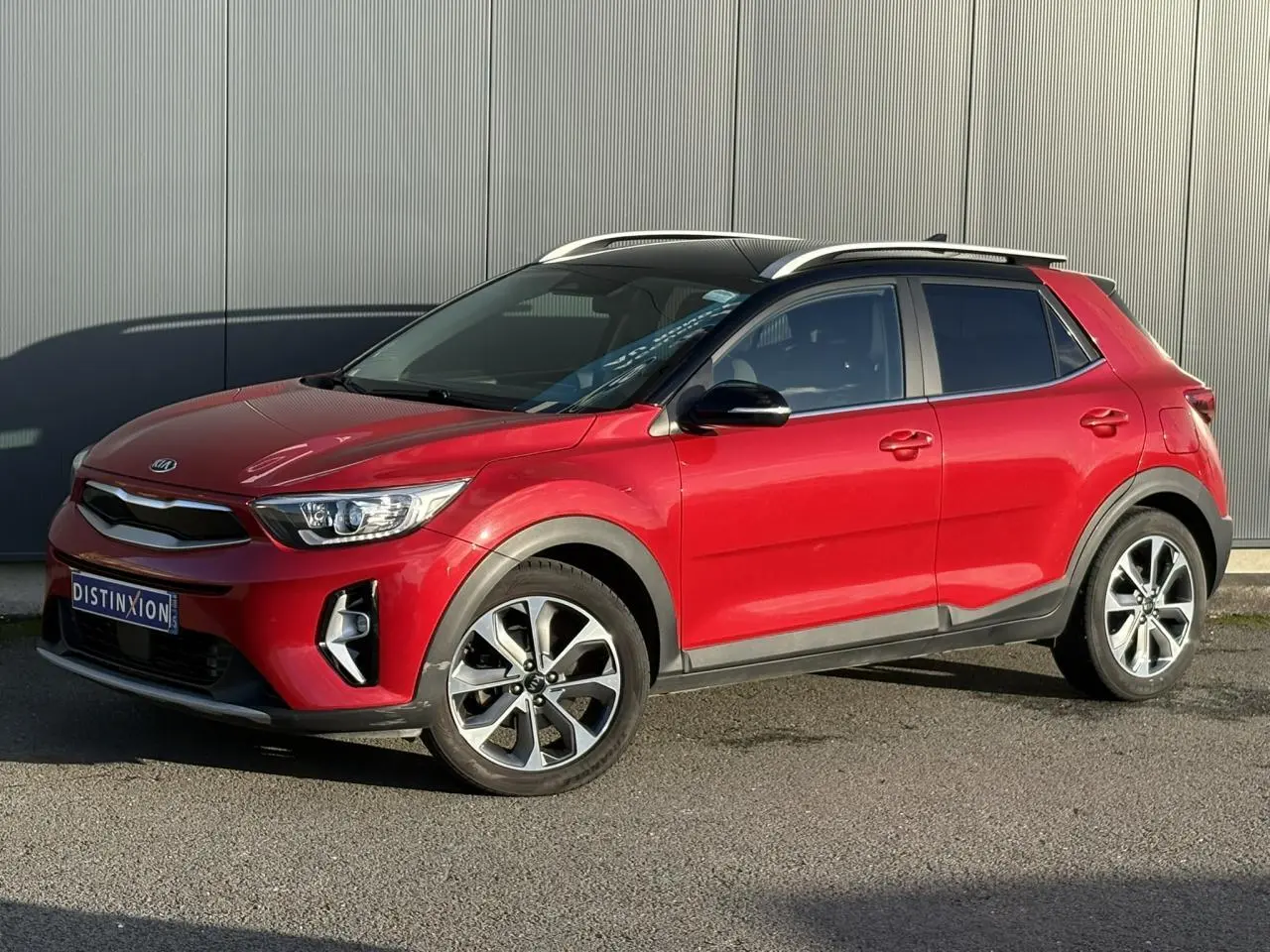 KIA Stonic rouge métallisé vue 3/4 avant droit avec jantes alliage et toit ouvrant panoramique.