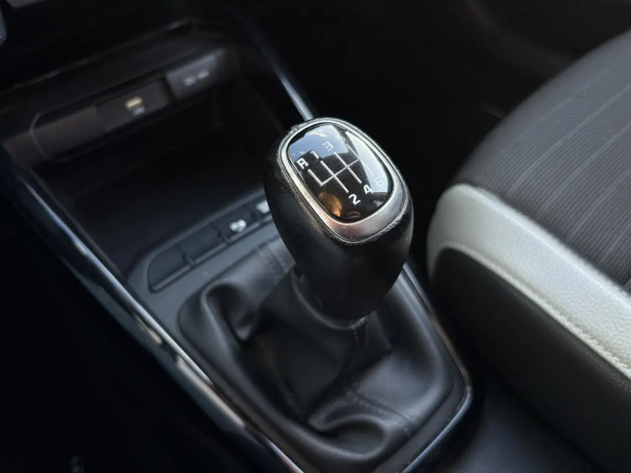 Vue rapprochée de la console centrale noire du Kia Stonic rouge, avec commandes climatisation et ports USB visibles.