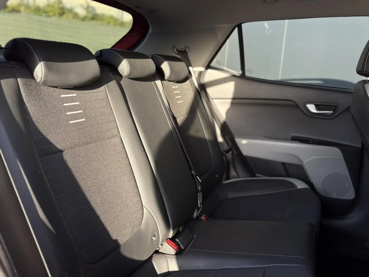 Coffre ouvert vu de l'arrière d'un KIA Stonic rouge, montrant l'espace de chargement et l'intérieur noir.