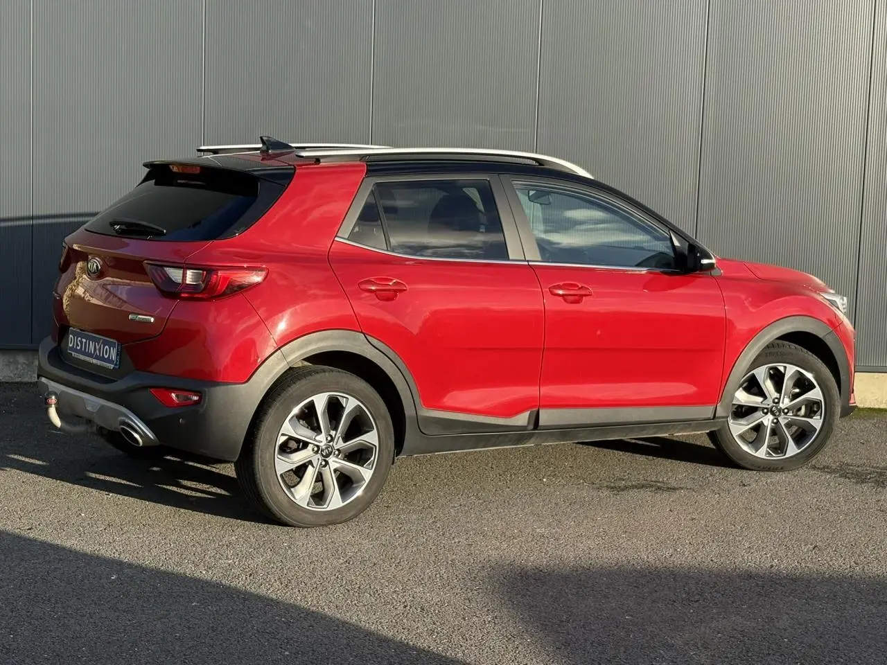 Vue 3/4 arrière droite d'un Kia Stonic rouge métallisé avec attelage et jantes alliage 17 pouces.