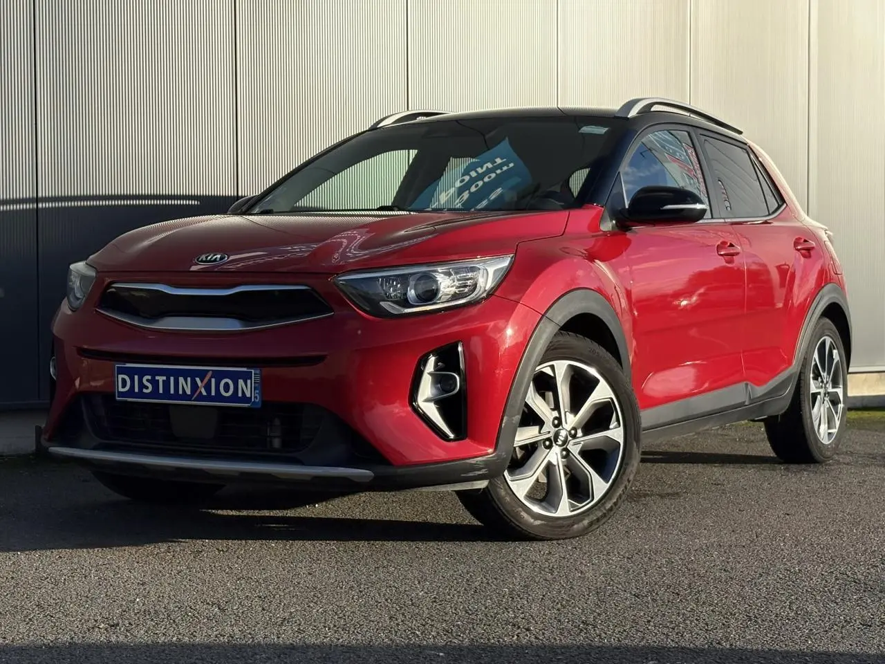 KIA Stonic rouge métallisé vue 3/4 avant droit avec toit noir et jantes alliage 17 pouces.