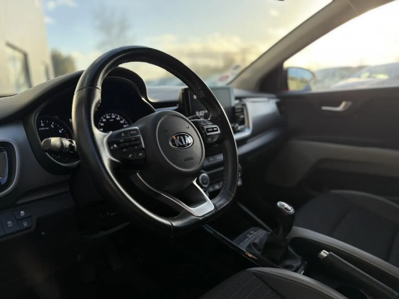 Vue intérieure frontale du tableau de bord et volant KIA Stonic avec écran tactile et boîte manuelle.