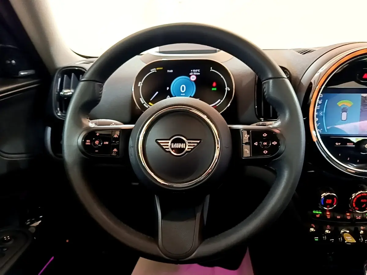 Vue intérieure centrée sur le volant cuir noir d'une MINI Countryman 2023 avec tableau de bord numérique et écran tactile.