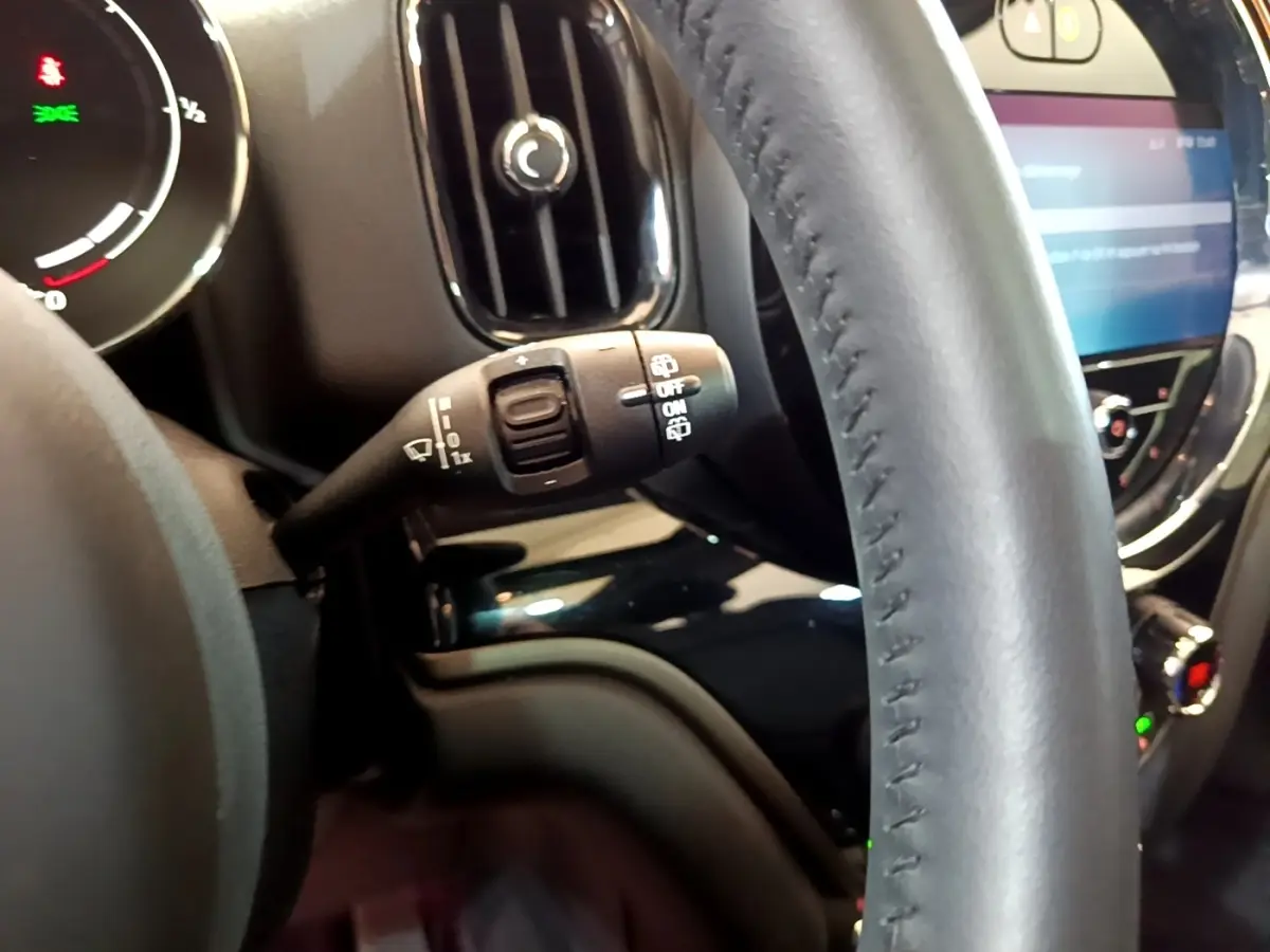 Gros plan sur le volant cuir noir et la commande d’essuie-glace du MINI Countryman Cooper SE hybride 2023.