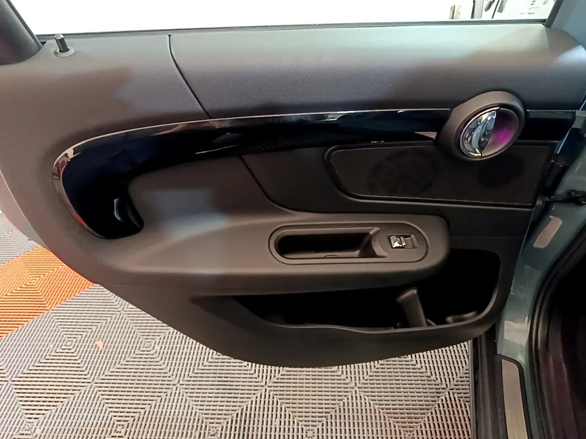 Vue rapprochée de la porte côté gauche verte du MINI COUNTRYMAN Cooper SE avec poignée et haut-parleur intégrés.