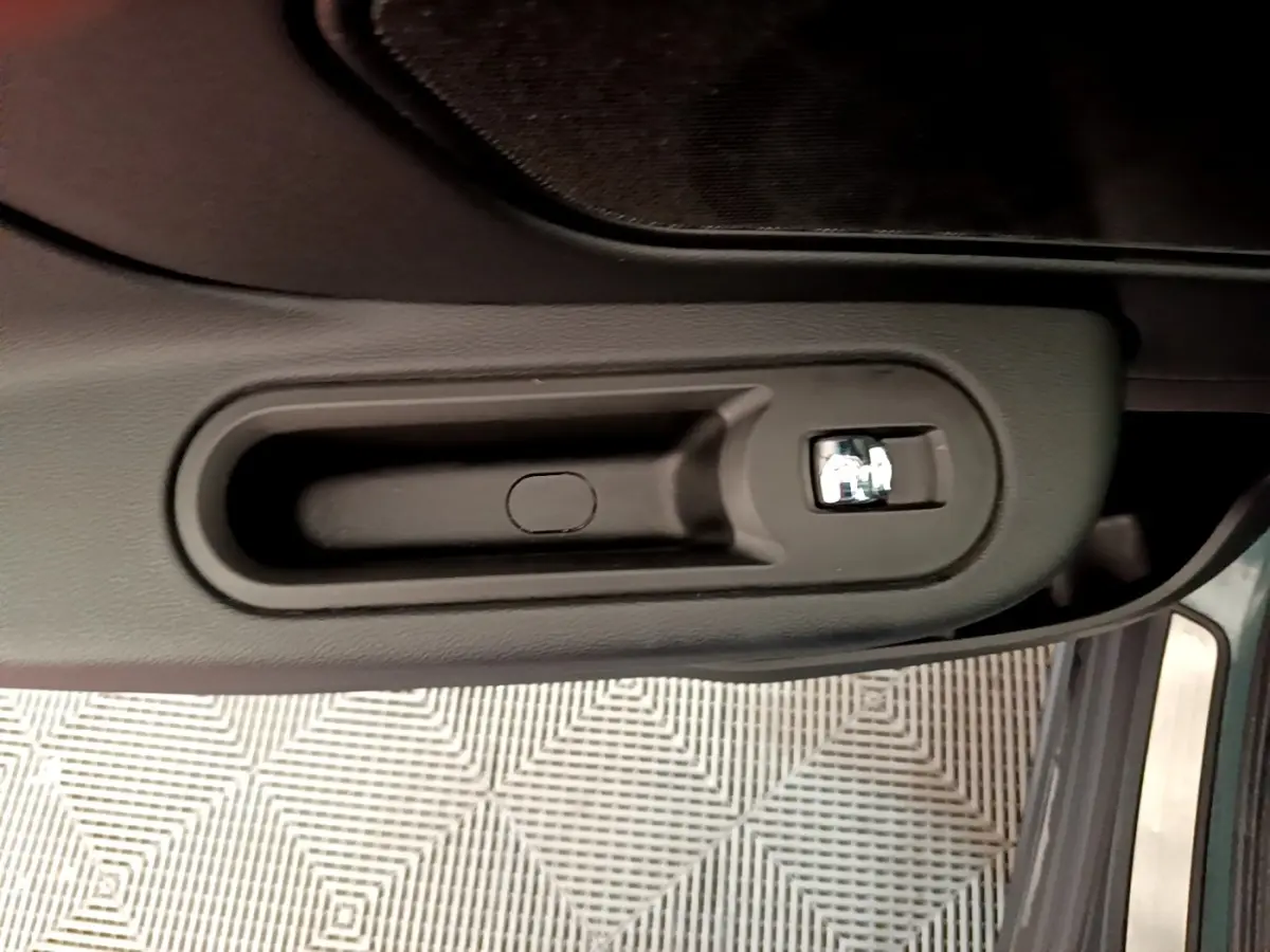 Poignée intérieure de porte côté conducteur du MINI Countryman vert 2023, avec bouton de verrouillage chrome.