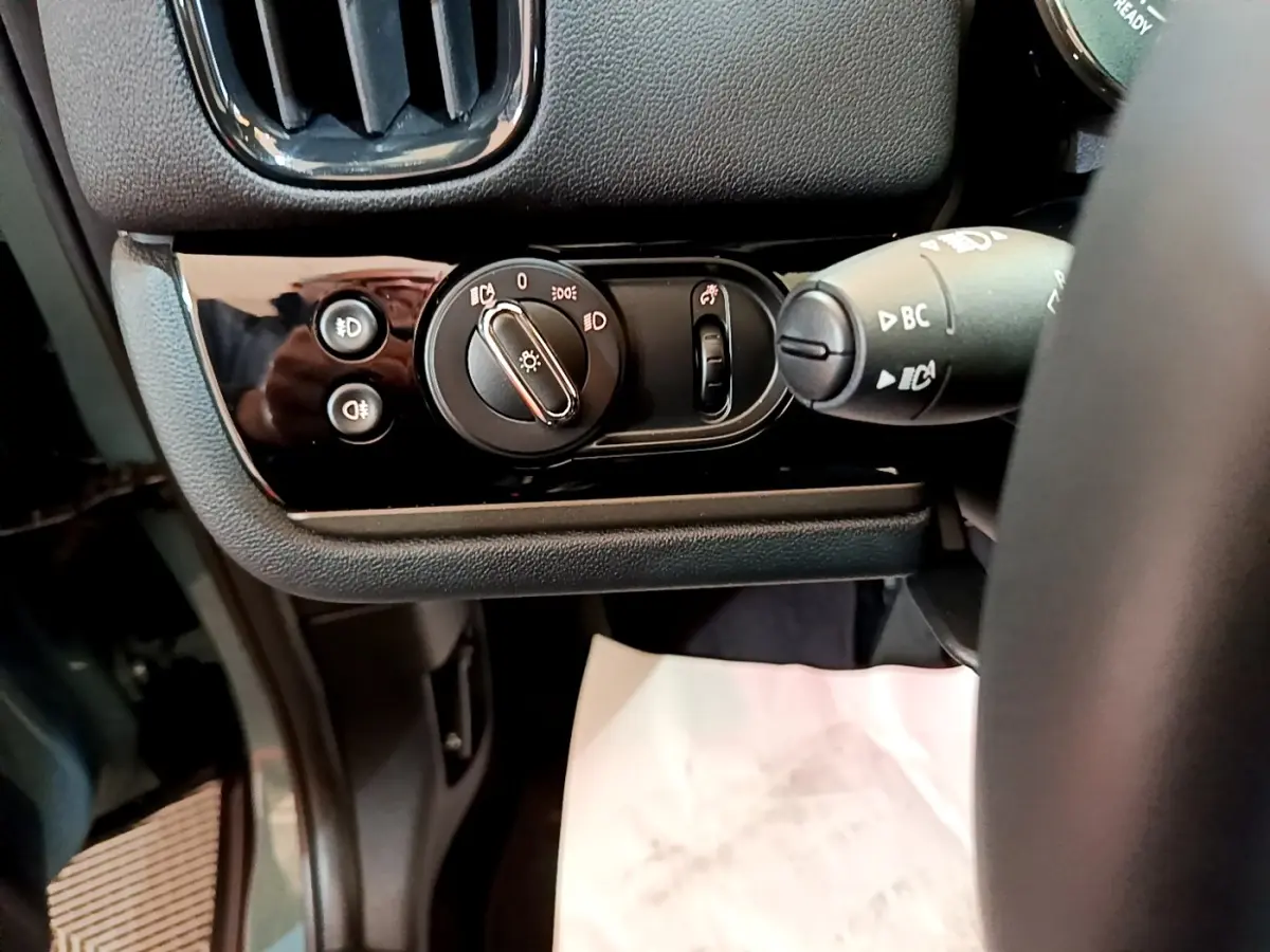 Gros plan sur les commandes d'éclairage côté gauche du tableau de bord noir du MINI Countryman vert 2023 hybride rechargeable