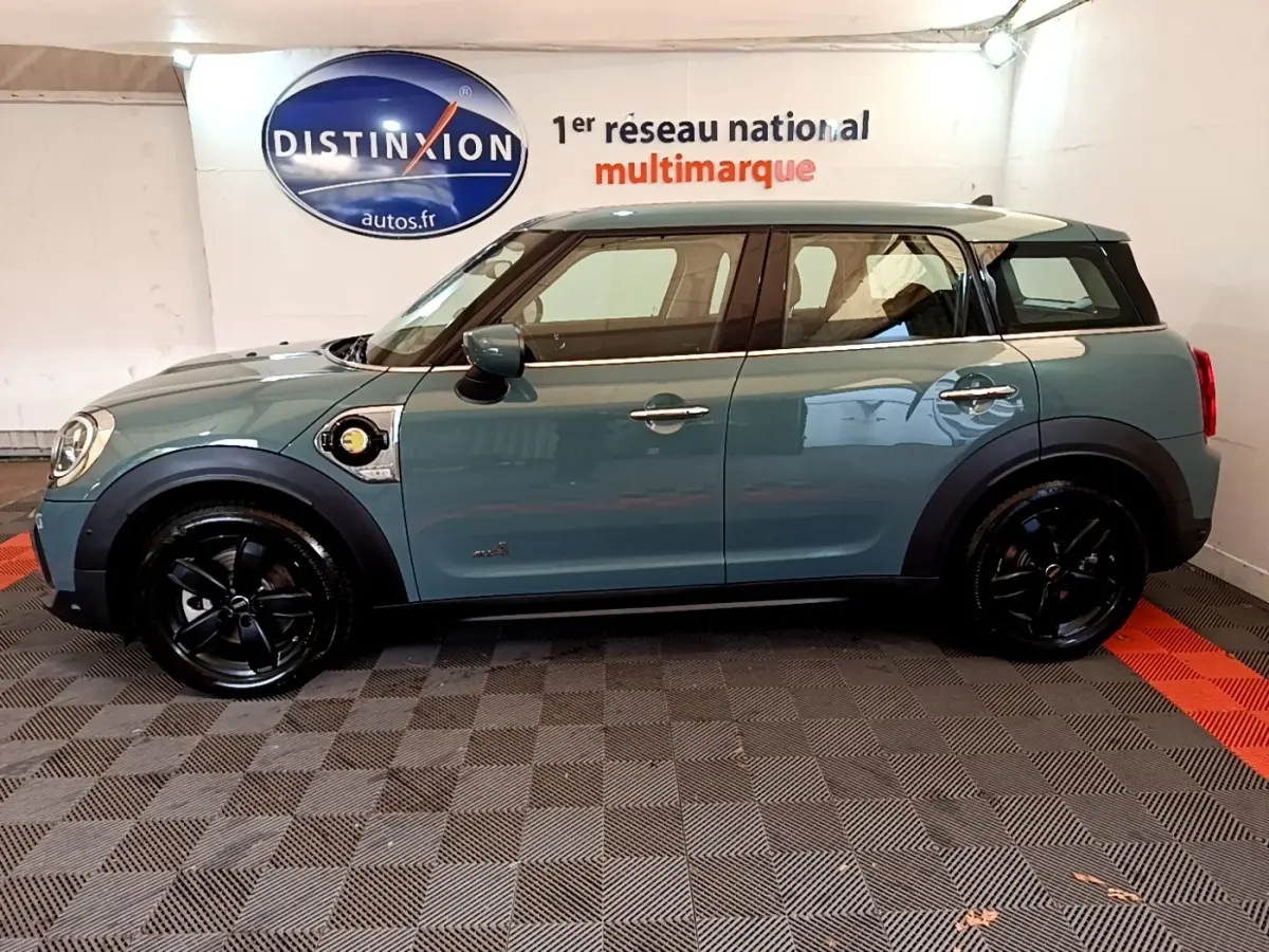Profil côté gauche d'une MINI Countryman Cooper SE hybride rechargeable verte avec toit blanc et jantes noires.