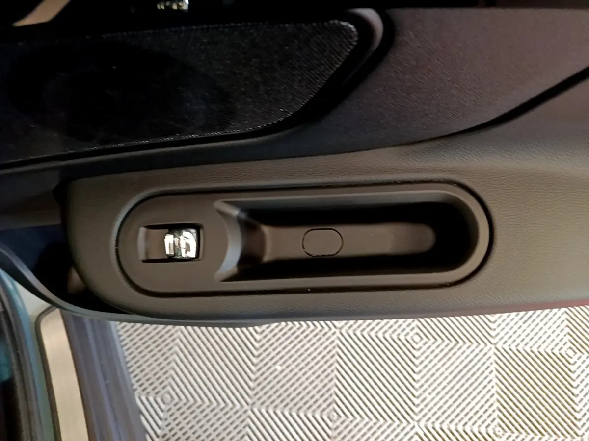 Poignée intérieure côté gauche de la MINI Countryman hybride rechargeable verte, vue rapprochée sur la commande de verrouillage.