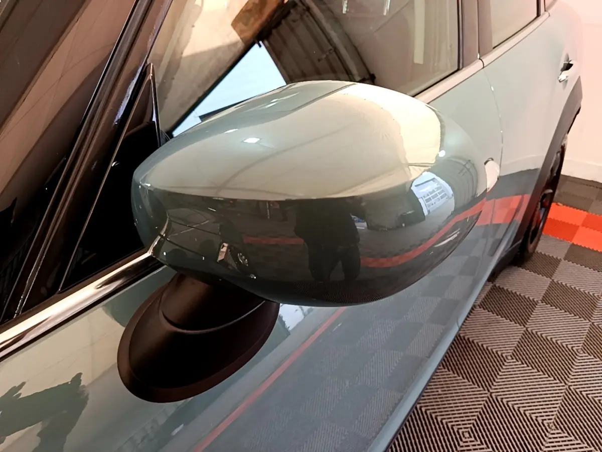 Rétroviseur côté gauche vert brillant du MINI Countryman 2023, vue rapprochée sur la portière et la poignée.