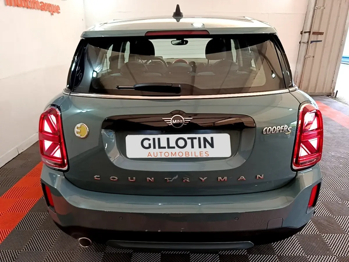 Vue arrière d'une MINI Countryman Cooper SE verte avec logo électrique et feux arrière LED allumés.