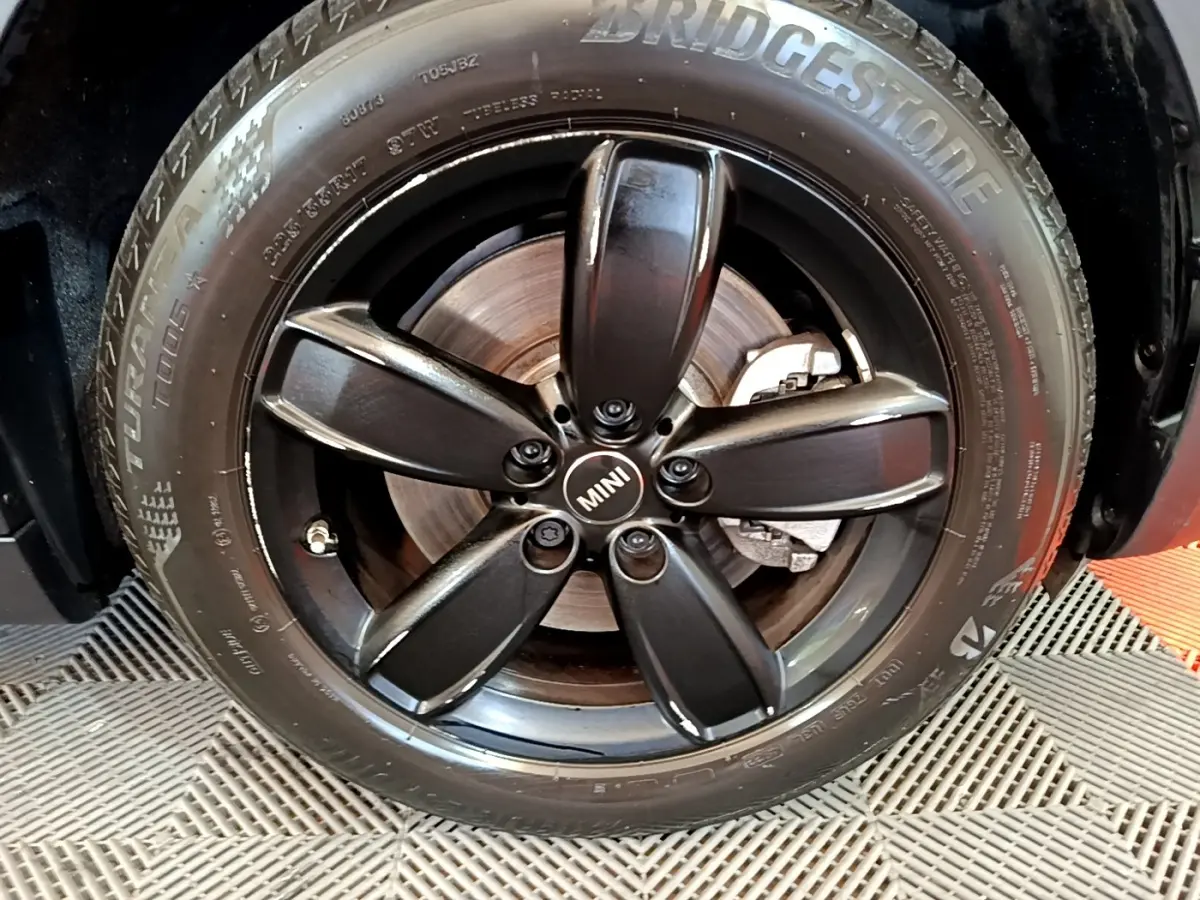 Gros plan sur la jante noire à cinq branches avec logo MINI au centre, montée sur un pneu Bridgestone.