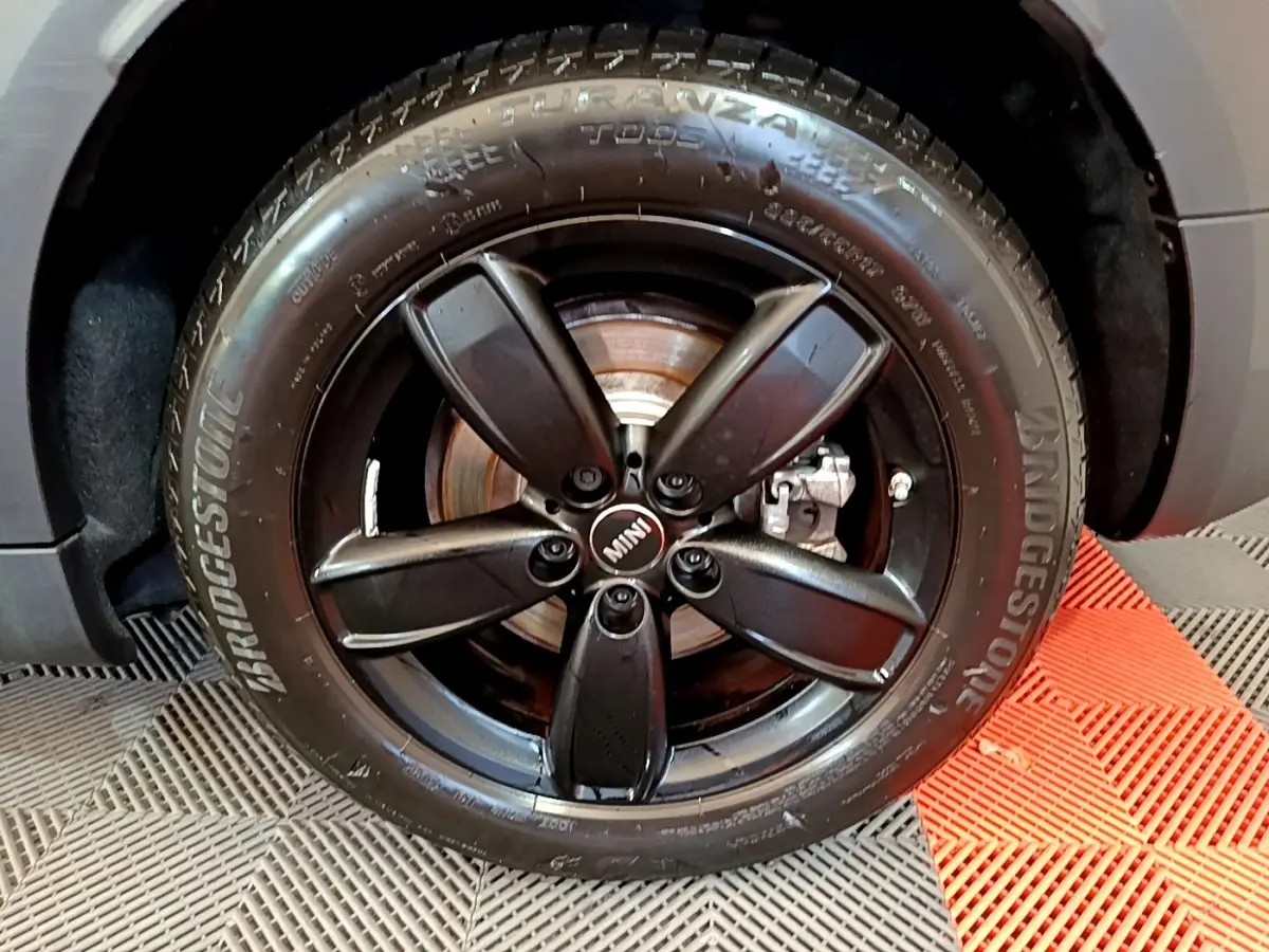 Gros plan sur la roue avant droite du MINI Countryman vert avec jante noire à cinq branches et pneu Bridgestone.