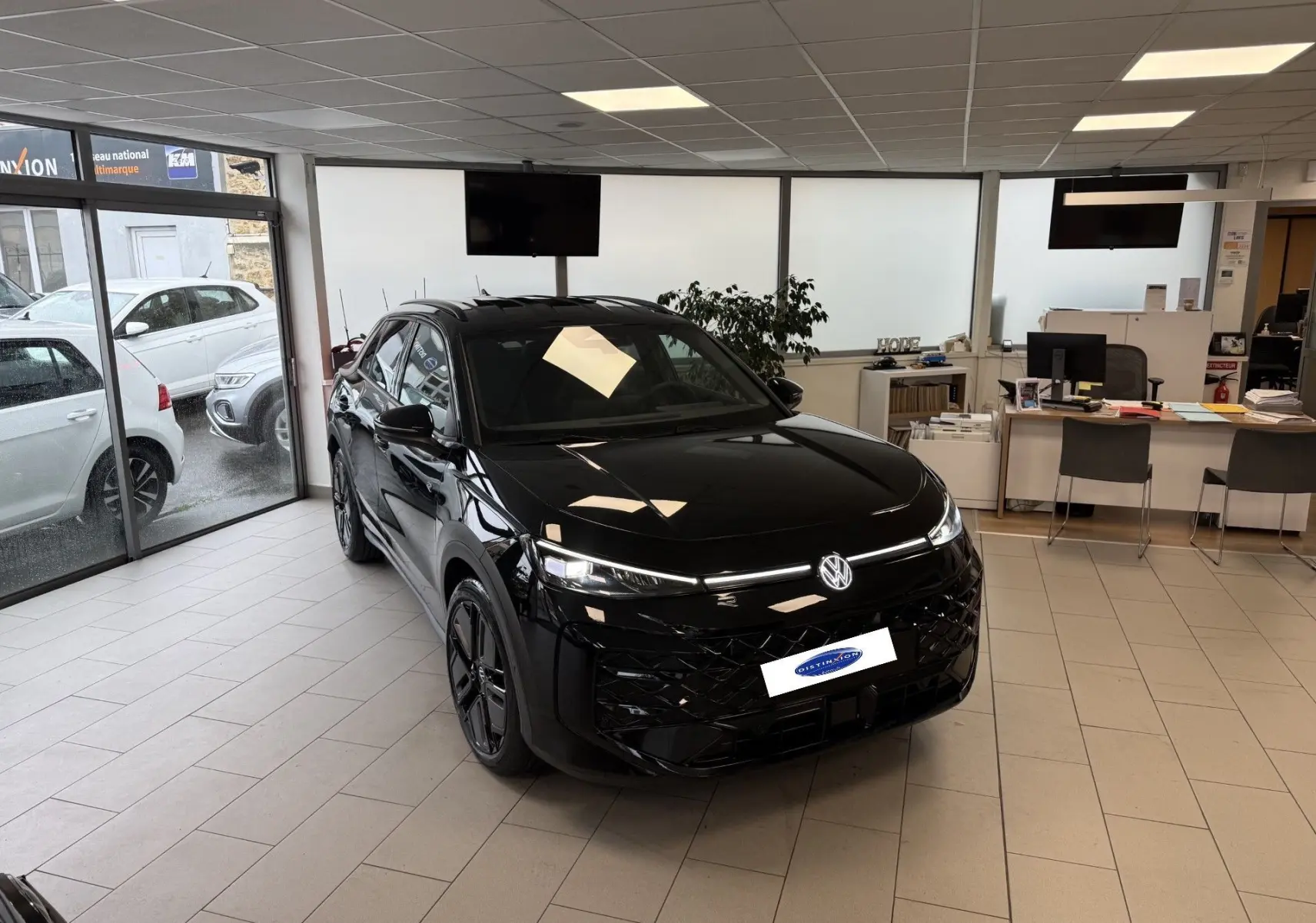 Volkswagen T-Roc Noir Intense en vue 3/4 avant droit dans un showroom avec jantes noires et calandre R-Line.
