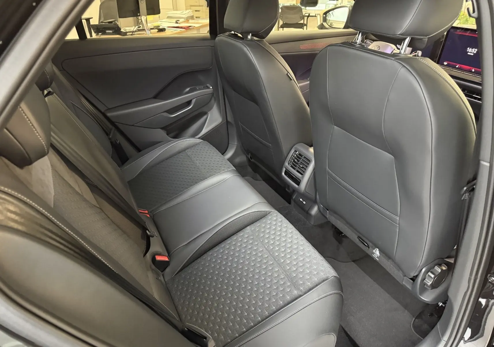 Vue intérieure arrière du Volkswagen T-Roc noir intense, montrant les sièges arrière en cuir et tissu avec aérateurs centraux.