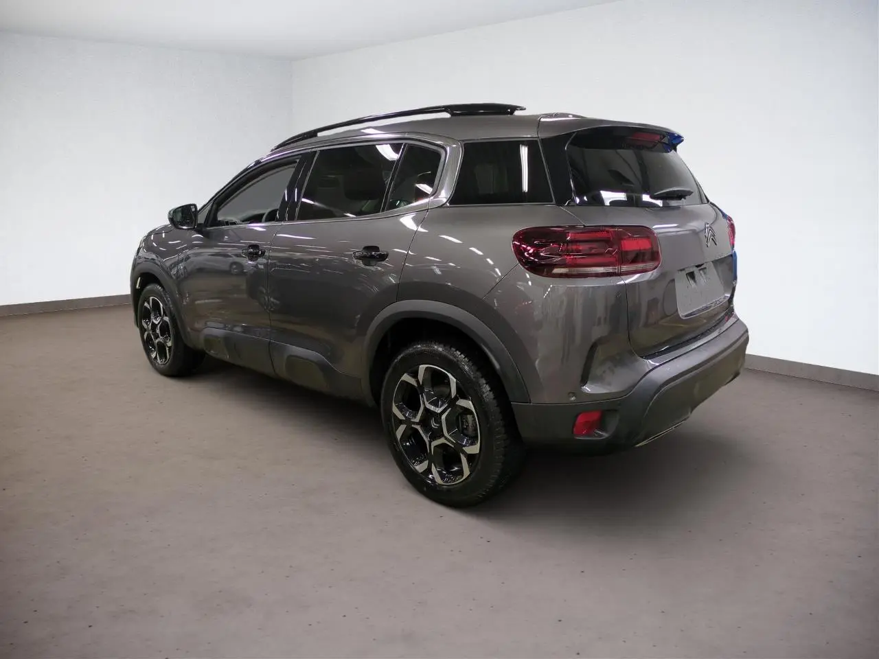 Vue 3/4 arrière droite du Citroën C5 Aircross Hybrid gris Platinium avec jantes alliage bi-ton et toit noir.