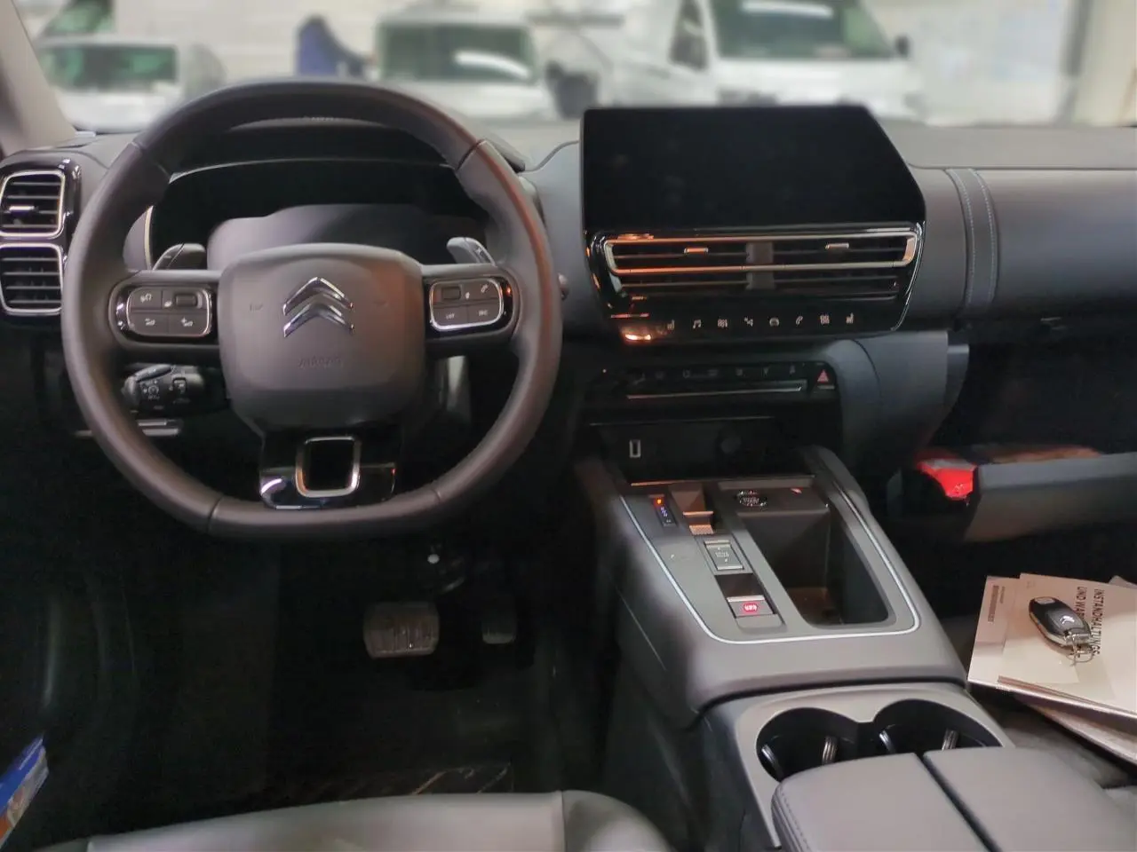 Vue intérieure avant du Citroën C5 Aircross Hybrid 2025, tableau de bord noir avec écran tactile et volant multifonction.