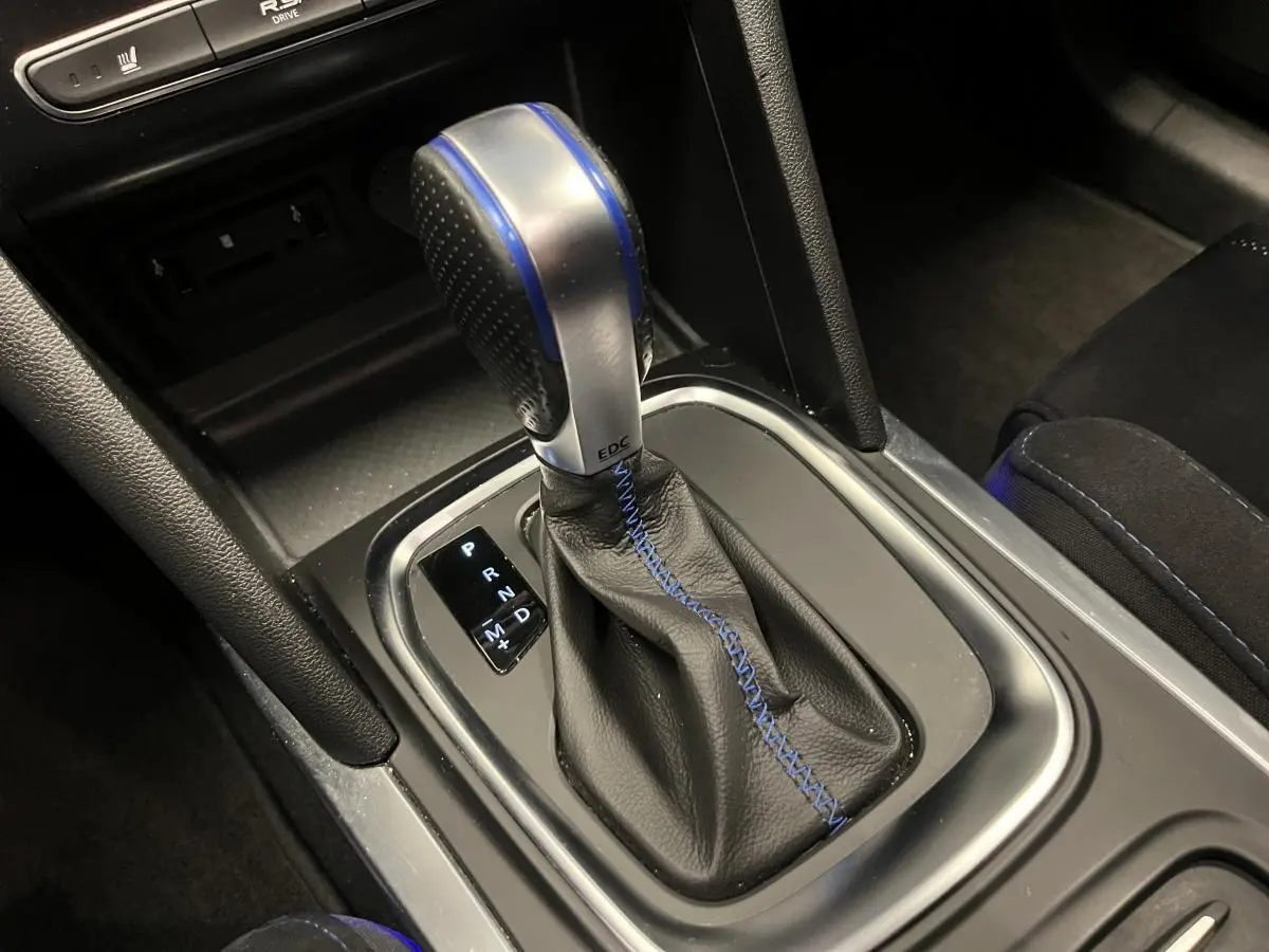 Gros plan sur le levier de vitesses automatique noir avec surpiqûres bleues de la Renault Mégane GT 2016.
