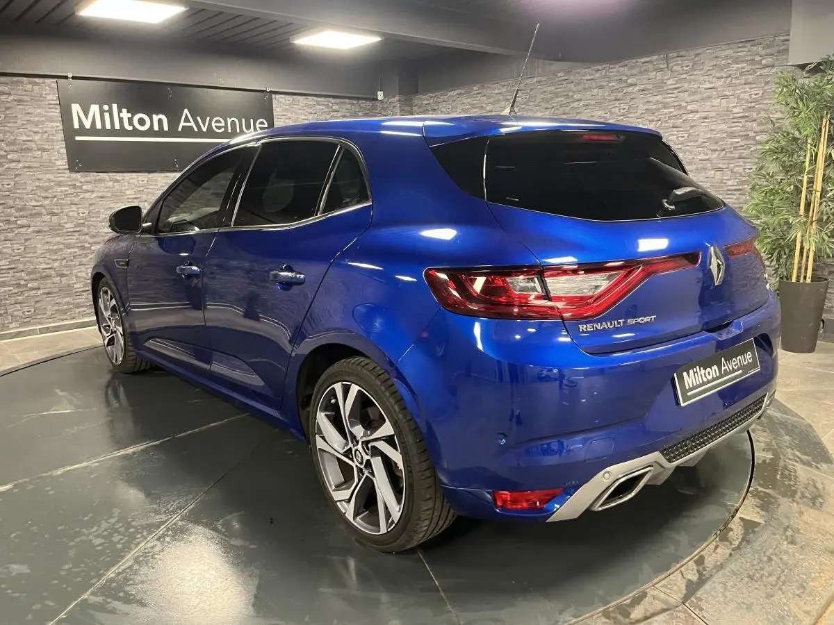 Vue 3/4 arrière droite d'une Renault Mégane GT bleu Iron avec jantes alliage 18 pouces et double sortie d'échappement intégrée.
