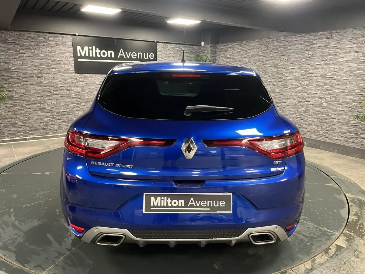 Vue arrière d'une Renault Mégane GT bleu Iron avec double sortie d'échappement et logo Renault Sport visible.