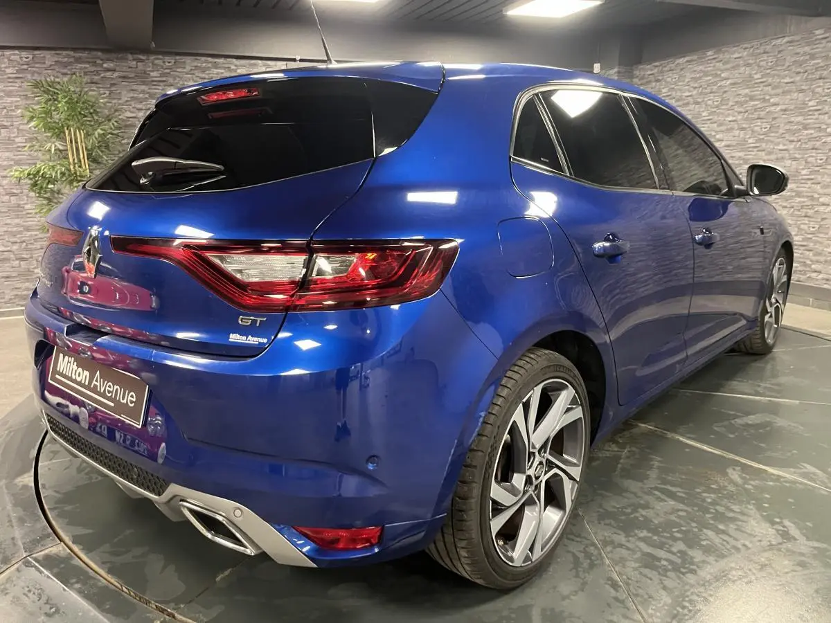 Vue 3/4 arrière droite d'une Renault Mégane GT bleue Iron avec jantes alliage 18 pouces et vitres surteintées.