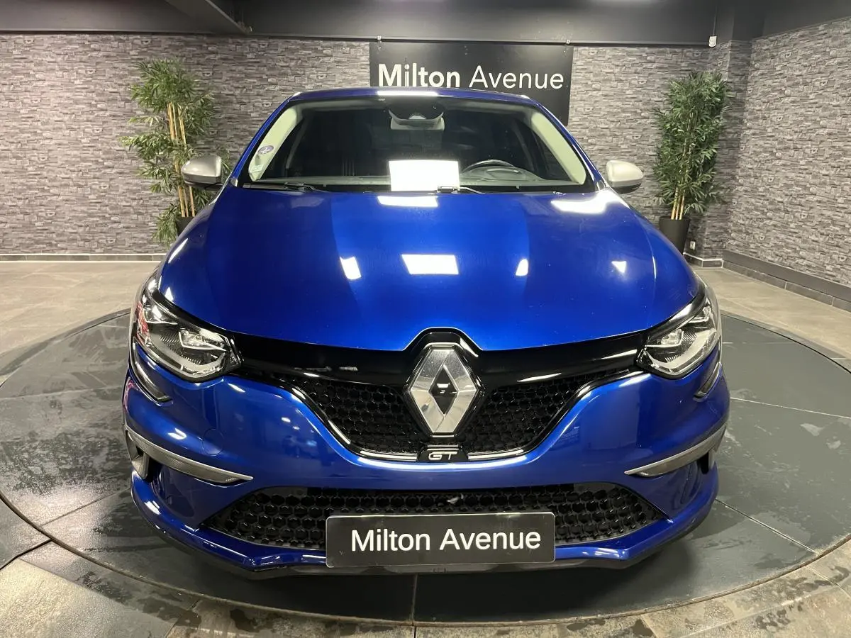 Vue avant d'une Renault Mégane GT bleu Iron avec calandre noire nid d'abeilles et logo Renault chromé.