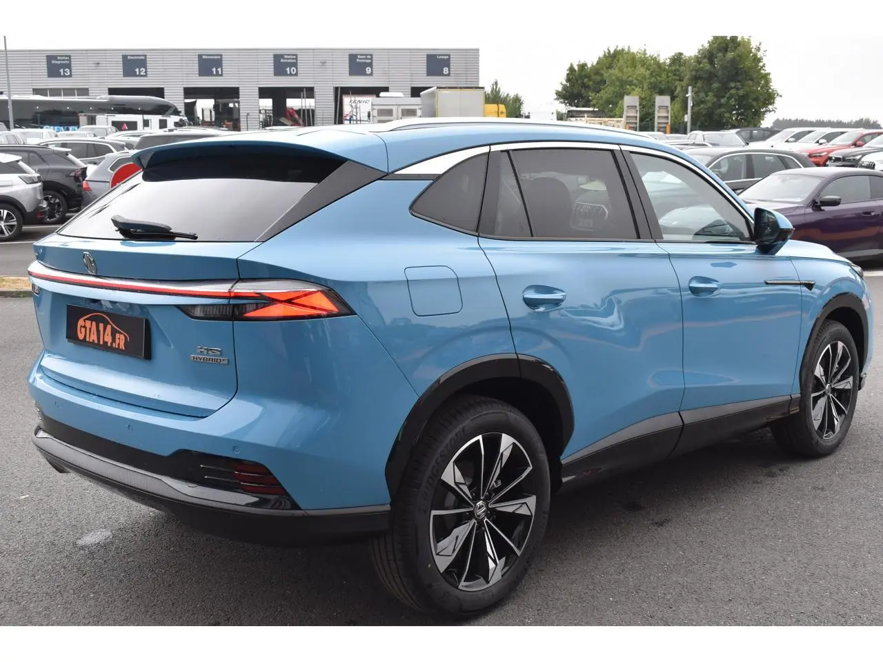 Vue 3/4 arrière droite du MG Motor EHS 1.5 Hybrid+ bleu 2026 avec feux arrière fins et jantes noires bicolores.