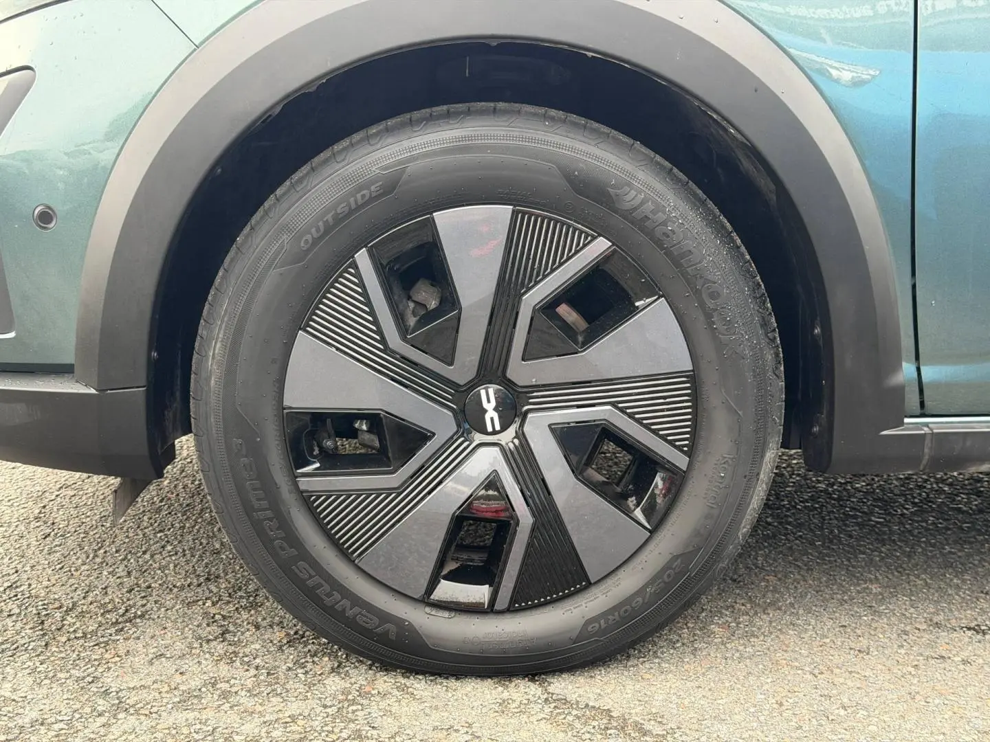 Gros plan sur la roue avant gauche du Dacia Jogger vert cèdre métallisé avec jante noire au design géométrique.