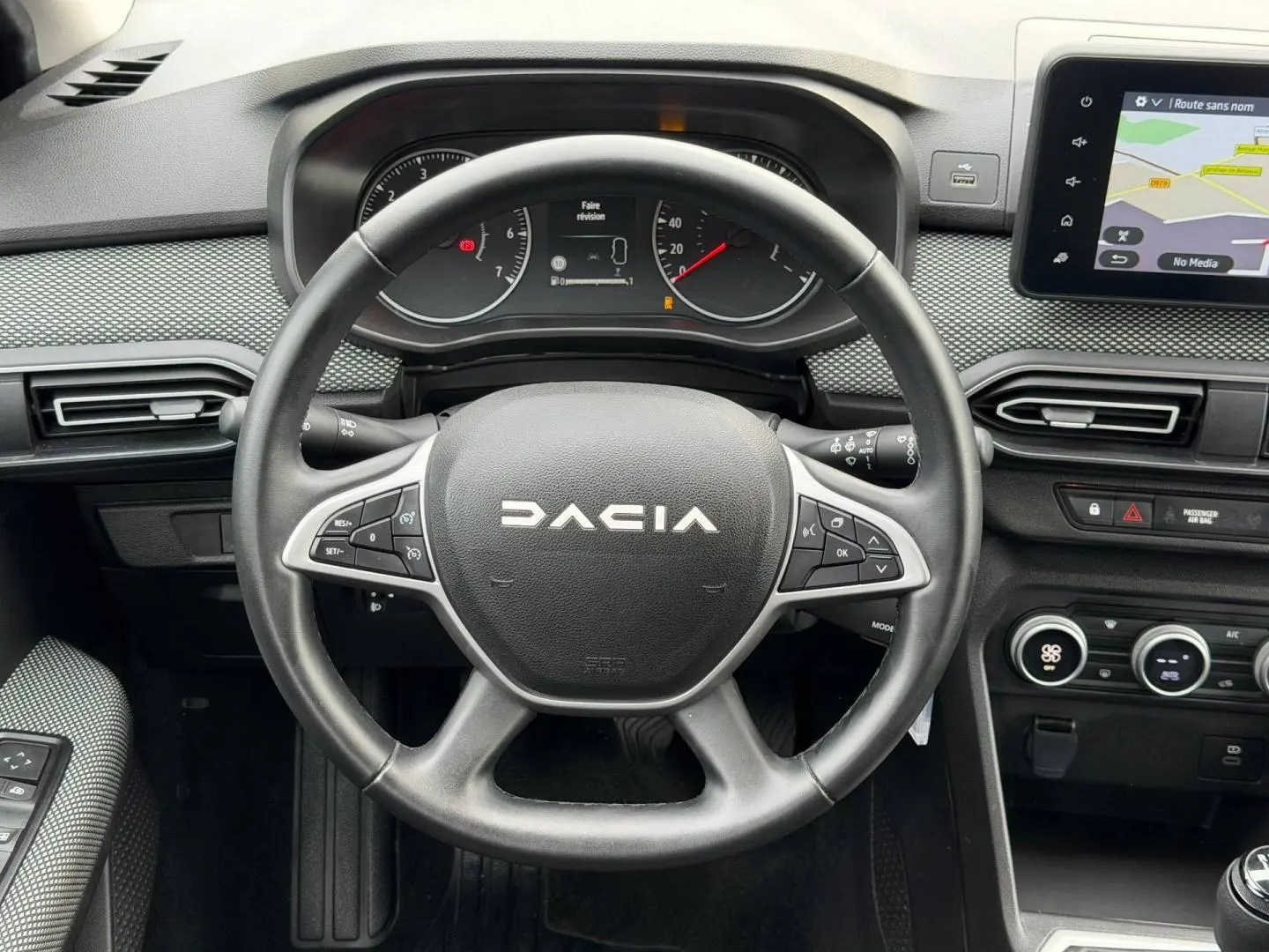 Vue rapprochée du volant et tableau de bord du Dacia Jogger 2025, avec écran tactile et commandes au volant visibles.