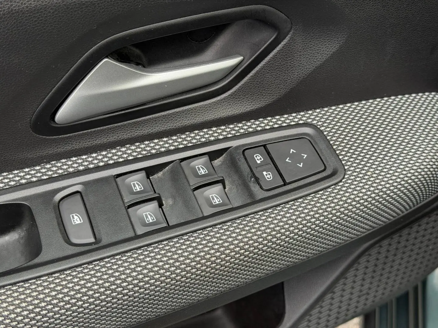 Gros plan sur la commande des vitres électriques et rétroviseurs sur la porte avant gauche du Dacia Jogger 2025.