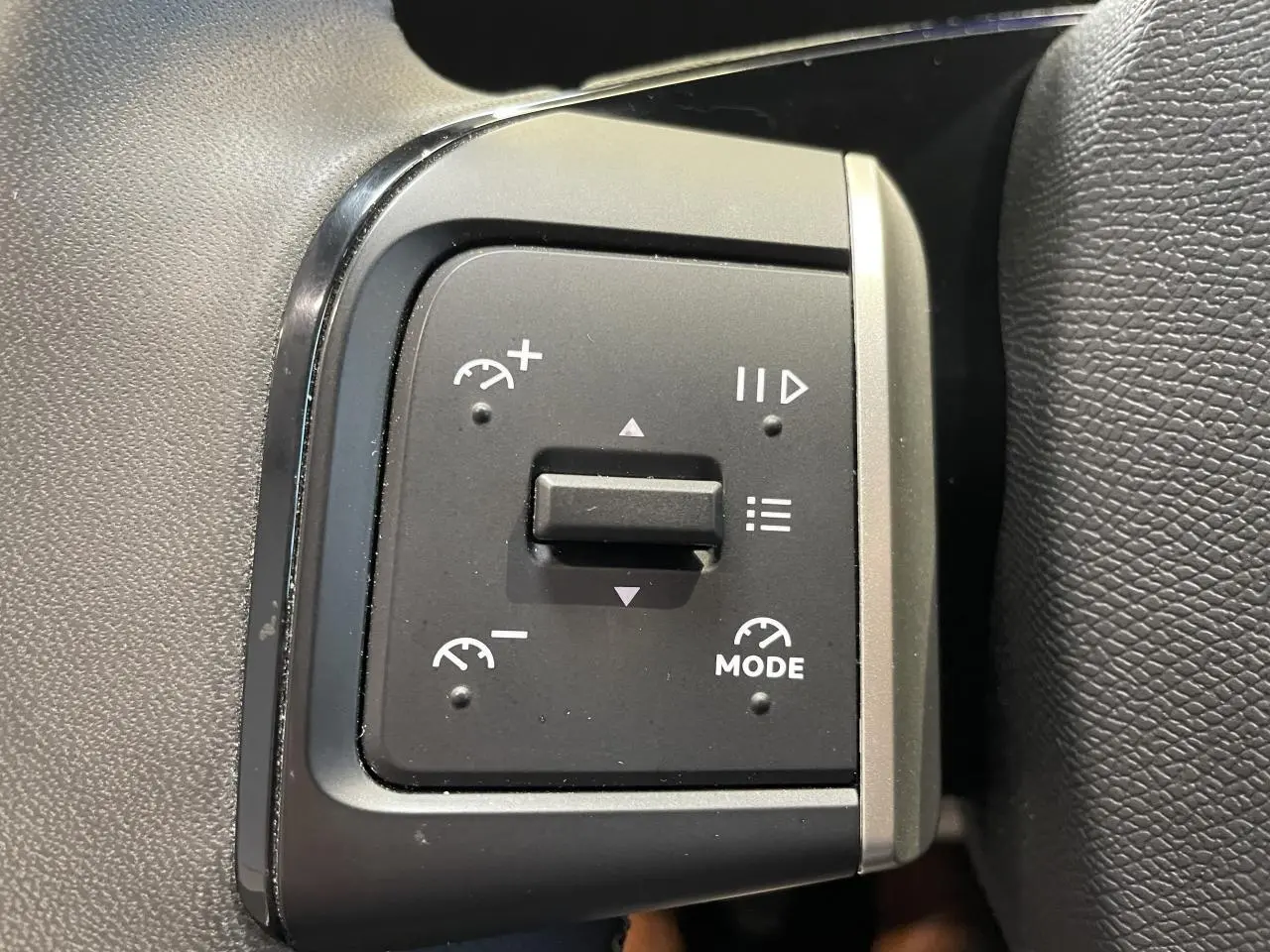 Gros plan sur les commandes de régulateur de vitesse à gauche du volant dans l’habitacle d’une Citroën C3 blanche.