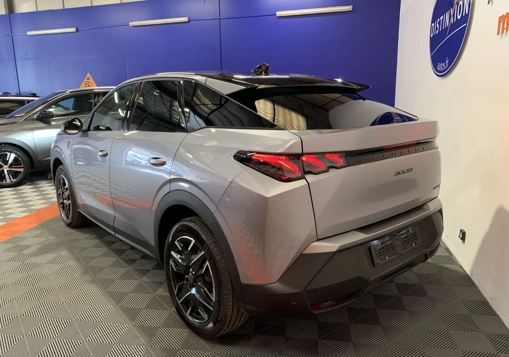 Peugeot 3008 III GT Hybrid gris Artense vue 3/4 arrière droit en intérieur avec toit noir brillant et feux LED distinctifs.