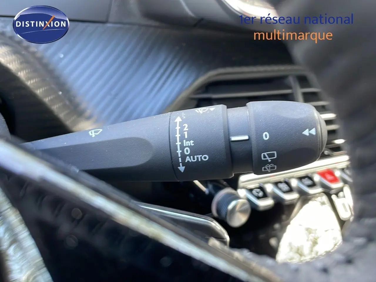 Gros plan sur la commande d'essuie-glace du Peugeot 2008 2025, avec tableau de bord noir texturé en arrière-plan.