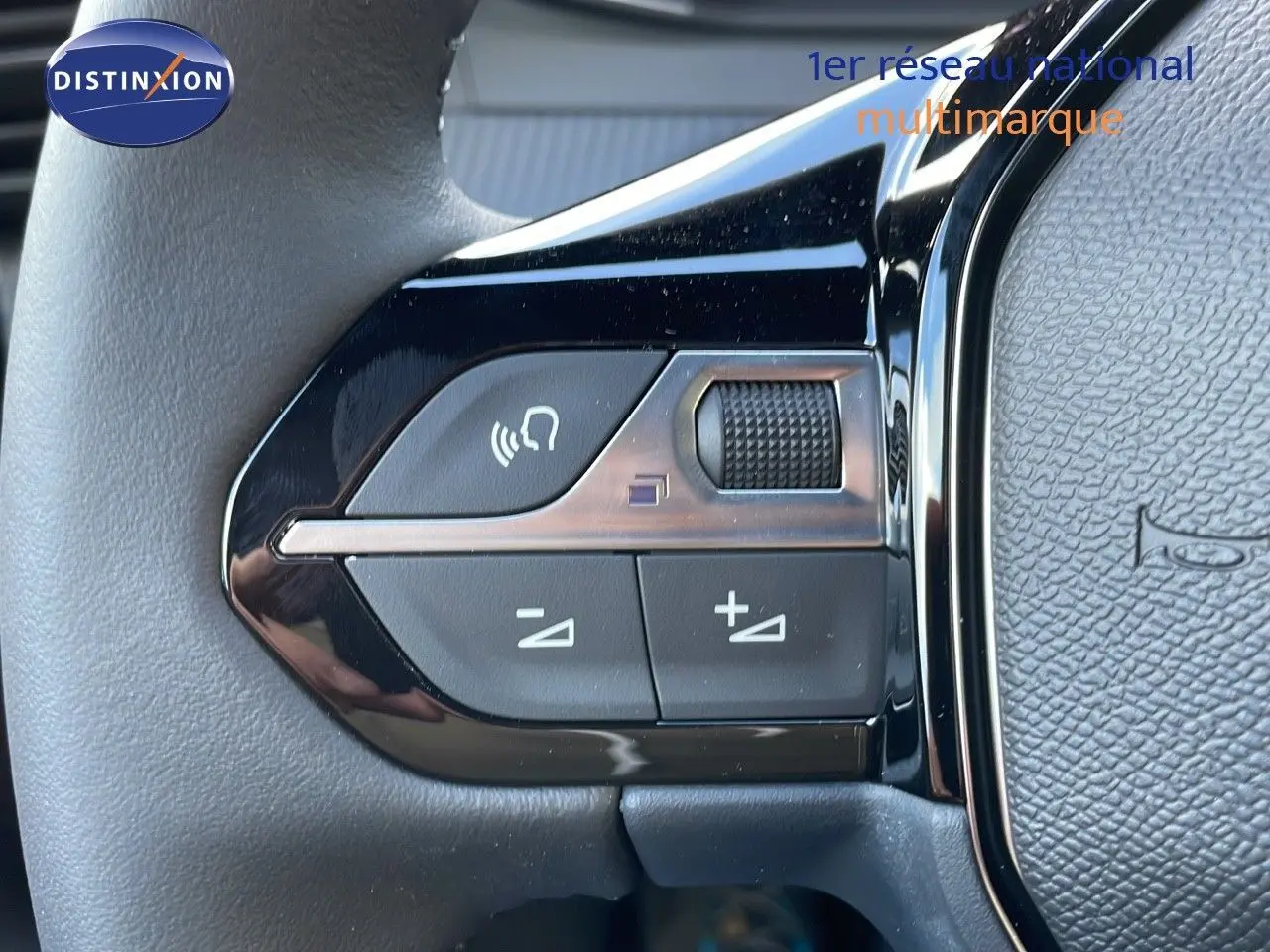 Gros plan sur les commandes de volume et appel du volant d'un Peugeot 2008 gris Artense Metal, version 2025.