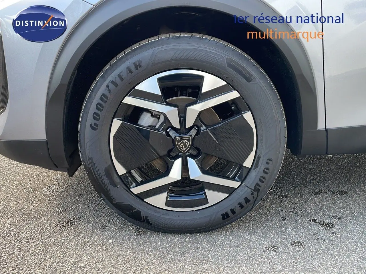 Gros plan sur la roue avant gauche du Peugeot 2008 gris Artense métal avec jante alliage bicolore moderne.