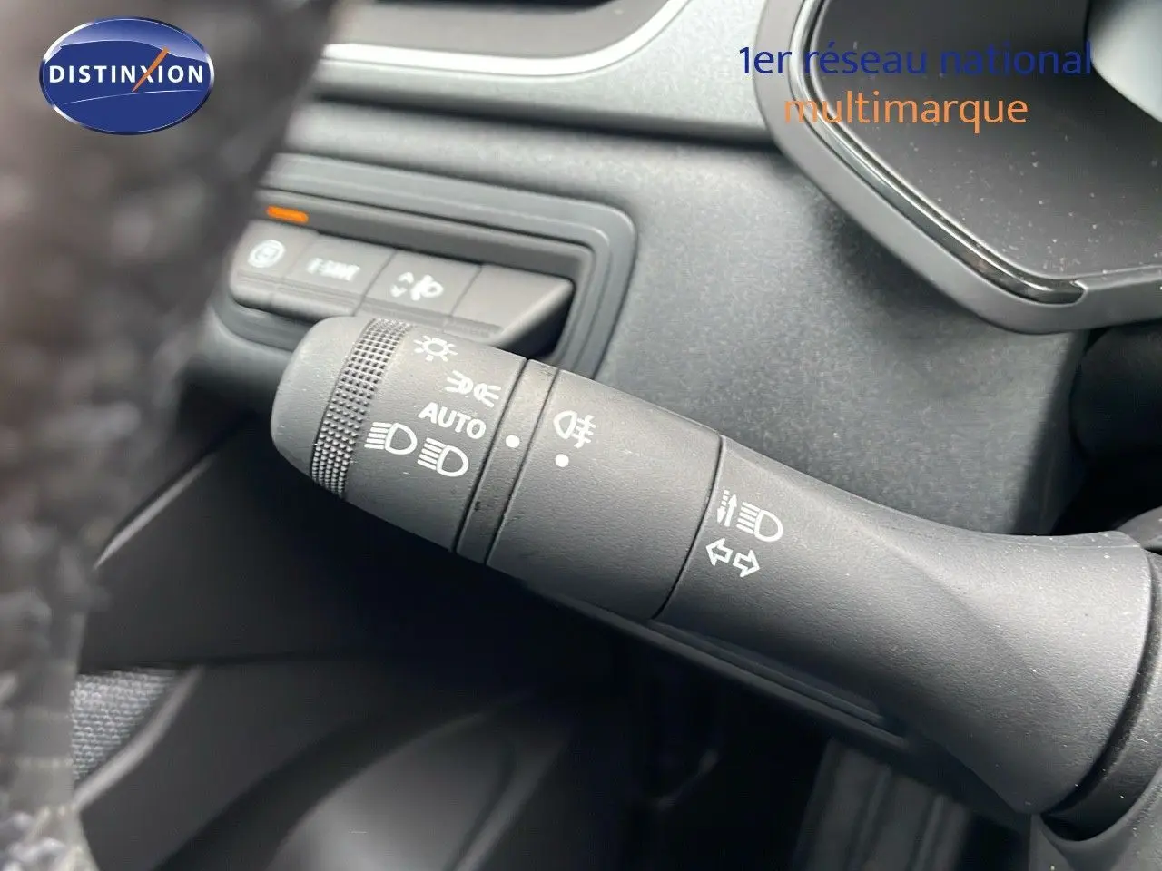 Gros plan sur la commande des feux et clignotants du Renault Captur E-Tech hybride 2025, intérieur noir.