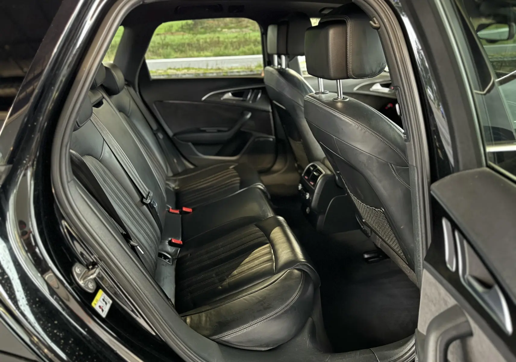 Vue intérieure arrière droite de l’Audi A6 Avant Allroad noire, sièges en cuir noir et finitions élégantes.