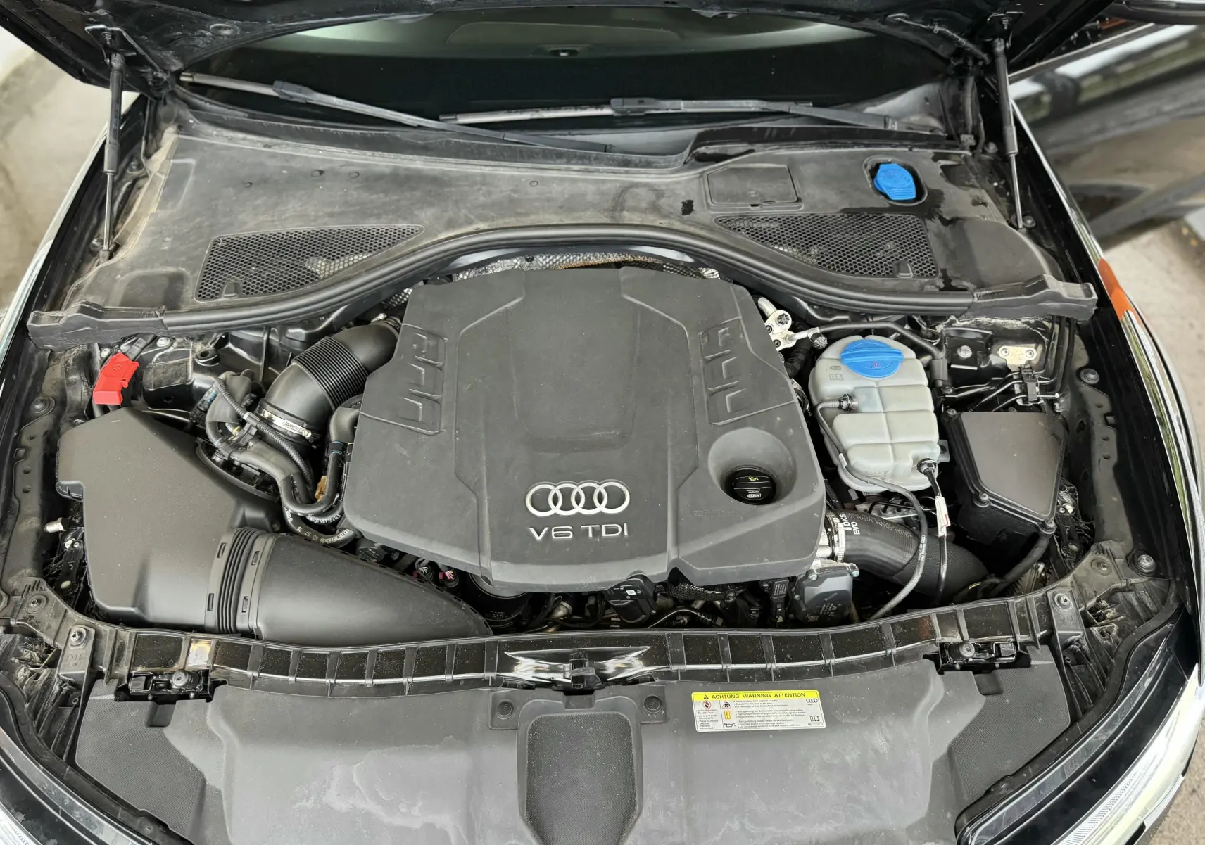 Vue plongeante sur le moteur V6 TDI d'une Audi A6 Avant Allroad noire, capot ouvert montrant le compartiment moteur.