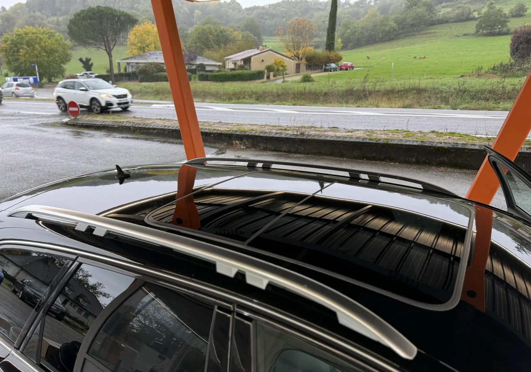 Vue rapprochée du toit ouvrant panoramique et des barres de toit argentées d’une Audi A6 Avant Allroad noire.