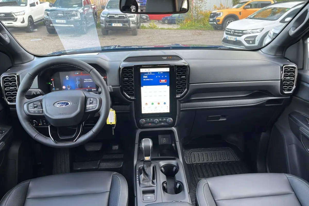 Intérieur du Ford Ranger 2025 vu de face, tableau de bord noir avec écran tactile vertical et volant multifonctions cuir.