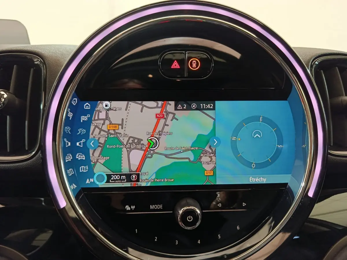 Écran tactile central du tableau de bord MINI Countryman Cooper SE blanc, affichant la navigation avec anneau lumineux violet.