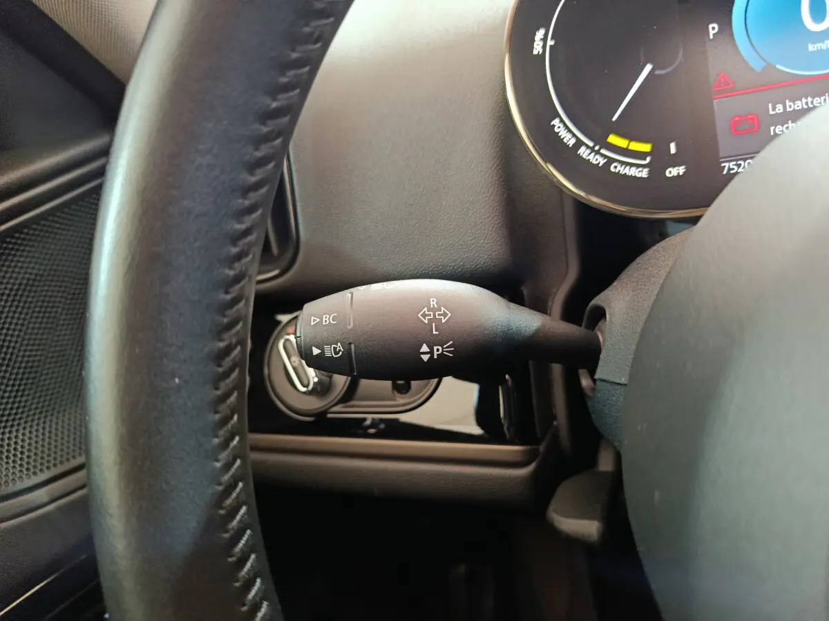 Gros plan sur la manette de clignotants côté gauche du volant noir dans l'habitacle d'une MINI Countryman blanche hybride rechargeable.
