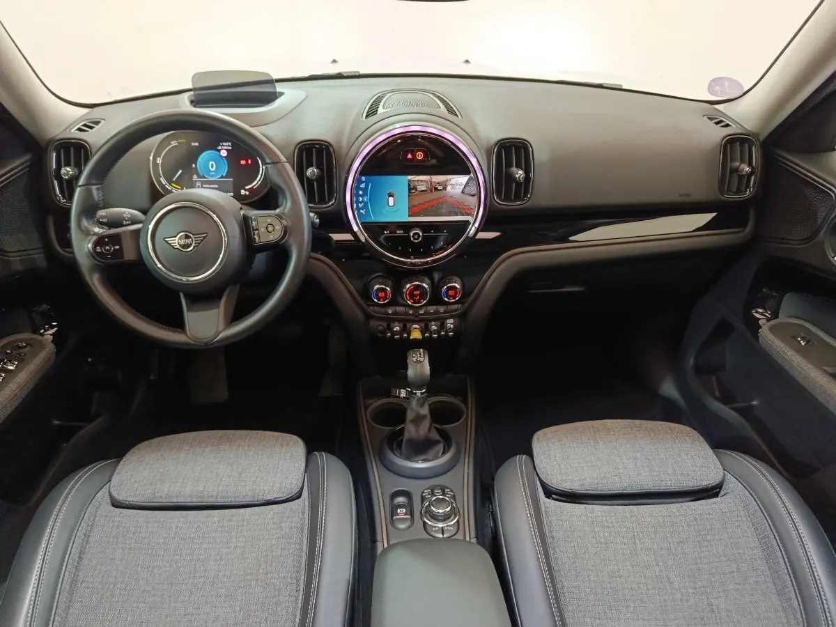Intérieur du MINI Countryman Cooper SE blanc, vue frontale du tableau de bord avec écran tactile rond et volant cuir.